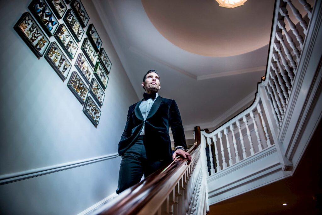 A model wearing a bespoke tuxedo walking down a staircase